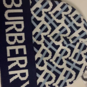 Mönstrad mössa från Burberry - Snygg mössa från Burberry med ett coolt mönster i blått och vitt. Perfekt för att hålla sig varm och stilren under kyliga dagar. Den har en bred kant med Burberry-loggan i vitt. Passar perfekt till både vardag och fest!
