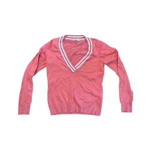 Rosa v-ringad tröja - Säljer en snygg rosa tröja från ginatracot med v-ringad hals och randiga detaljer i vitt och blått. Perfekt för vår och sommar! Tröjan har långa ärmar och är i bra skick. Passar perfekt till jeans eller kjol för en avslappnad look.
