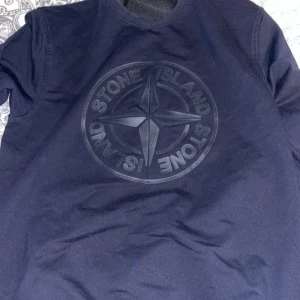 Mörkblå tröja från Stone Island - Säljer en snygg mörkblå tröja från Stone Island med deras ikoniska kompassmärke på bröstet. Perfekt för en stilren och avslappnad look. Tröjan är i bra skick och passar både till vardags och fest. Skicka ett meddelande vid intresse!