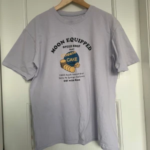ljus t-shirt med tryck - säljer en ljuslila t-shirt köpt på second-hand, ingen storlek men skulle gissa på strl M (man), oversized och går strax över rumpan på mig som vanligtvis har S/är 163cm!