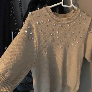 Beige stickad tröja från Zara - Säljer en superfin beige stickad tröja från Zara. Den har glittriga pärlor över axlarna och bröstet som ger 