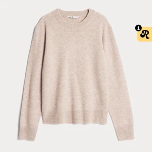 Beige stickad tröja - Mysig beige stickad tröja i ett mjukt material. Perfekt för kyliga dagar med sin avslappnade passform och ribbade detaljer vid hals, ärmslut och nederkant. Enkelt att matcha med jeans eller kjol för en stilren look.