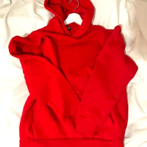 Röd hoodie från FSBN - Perfekt för kyliga dagar med sin mjuka insida och praktiska ficka framtill. Perfekt för både vardag och avslappnade tillfällen.