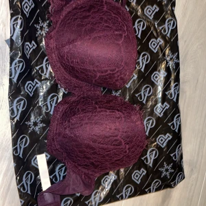 Vinröd spets-bh från Victoria's Secret - Säljer en elegant vinröd bh från Victoria's Secret i spets. Den har justerbara axelband och en klassisk hakknäppning i ryggen. Perfekt för en lyxig känsla under kläderna. Helt ny och oanvänd, fortfarande i originalförpackning.