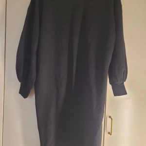 Svart långklänning från 152 - Säljer en stilren svart långklänning från märket 152. Klänningen har långa ärmar och en rund halsringning. Perfekt för höst och vinter, och kan enkelt stylas upp eller ner beroende på tillfälle. Materialet känns mjukt och bekvämt mot huden.