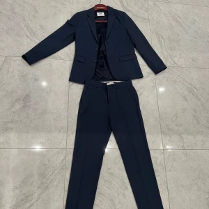 Mörkblå kostym från Zara - Säljer en stilren mörkblå kostym från Zara i storlek 11-12 år. Perfekt för festliga tillfällen eller skolavslutningar. Kostymen är i mycket bra skick och ger en elegant look.