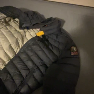  Parajumper jacka  - Säljer en snygg svart dunjacka från Parajumpers i storlek  M. Jackan är superlätt och perfekt för kyliga dagar. Den har en dragkedja framtill och en cool patch på ärmen. Perfekt för både höst och vinter!