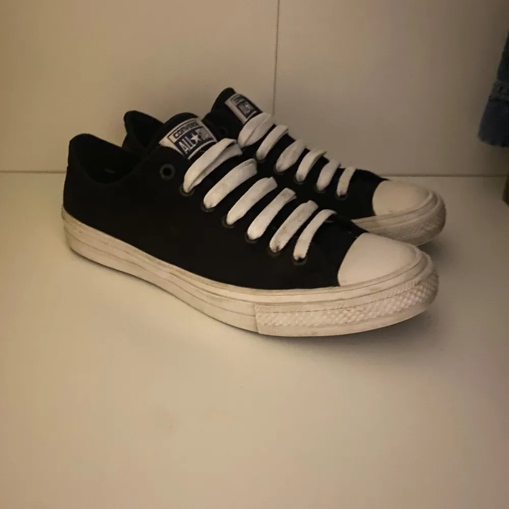 Säljer ett par klassiska svarta Converse All Star sneakers i bra skick. De har vit snörning och en vit sula som ger en snygg kontrast. Perfekta för vardagsbruk och passar till nästan alla outfits. Storleken 43, men passar även 44! Hör av dig vid frågor o funderingar!. Skor.