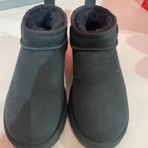 Svarta boots från UGG - Säljer ett par svarta UGG boots i storlek 37. De är i mycket bra skick och har en mysig pälsfodring som håller fötterna varma. Perfekta för kalla vinterdagar. De är gjorda av mocka och har en klassisk design som passar till det mesta. Använt dem 2 gånger och säljer pga att dem är förstora för mig!