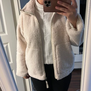Beige teddyjacka  - Mysig beige teddyjacka. Perfekt för kyliga dagar med sitt fluffiga material och dragkedja framtill. Jackan har en avslappnad passform och långa ärmar, vilket gör den idealisk för både höst och vinter. Superbekväm och trendig!