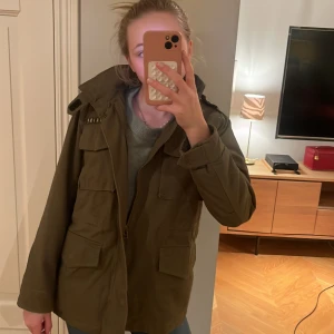 Olivgrön jacka från Zadig & Voltaire - Säljer en snygg olivgrön jacka från Zadig & Voltaire. Den har coola broderade detaljer på ryggen och en praktisk dragkedja framtill. Perfekt för höst och vår med sin normala passform och långa ärmar. Jackan har flera fickor och en stilren design.Mitt namn är skrivet på lappen men inget som stör, små hål i fickorna men inget jag har stört mig på, insidan är av mjuk vit lurv och ärmarna av satin på insidan, så hlller värmen