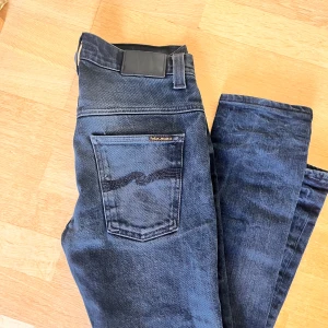 Svarta jeans från Nudie  - Säljer ett par mörkblå jeans från Nudie Jeans i bra skick. De har en slim passform  och är tillverkade i denim. De har feta slitningar Perfekta för både vardag och fest! 🕺29/34 men passar mer 29/32 