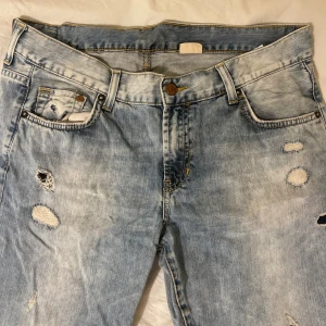Slitna low waist jeans - Säljer ett par ljusa jeans med slitningar. Dem är low waist och raka baggie om man har storlek S och mer storlek M om dem ska vara tightare i midjan. Köpta second hand:)