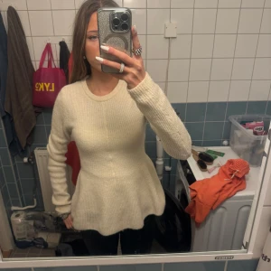 Vit stickad tröja från H&M - Säljer en superfin vit stickad tröja från H&M. Den har en peplumdesign som ger en snygg siluett och är perfekt för både vardag och fest. Tröjan är långärmad och i ett mjukt material som håller dig varm under kyliga dagar. Perfekt för höst och vinter! 