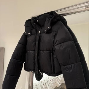 Svart pufferjacka med huva - Säljer en svart pufferjacka i mycket bra skick. Den är från boohoo och i storlek 36 +frakt