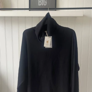 Svart polotröja - En stickad tröja i mjuk kashmir med avslappnad passform. Tröjan har ribbstickad polokrage, nedhasad axel och extra lång ärm. Ribbstickad kant vid ärmslut och nedtill. Ordinarie pris 1799 kr