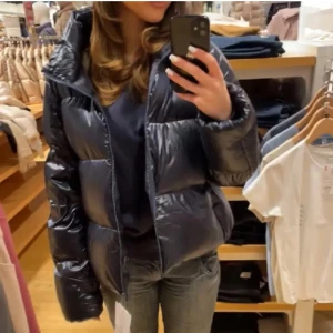 Blå glansig pufferjacka - Köpt på Plick för ca en månad sen är i bra skick. Syns att den är använd 
