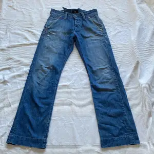 Säljer ett par snygga blå jeans i så fin sliten tvätt från Lee! Välanvända men i bra skick förutom att en knapp i gylfen saknas (dock inget jag tkr märks när de är stängda) och att de är slitna längst ner vid hälarna. Midja ca. 39cm men går att justera både mindre och lite större med spännet där bak. 