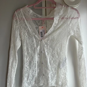 Spets topp - Vit spets topp från Nelly. Aldrig använd med prislappar kvar.  Lite stor i storleken. Nypris: 399