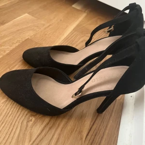 Svarta klackskor med remmar - Säljer ett par eleganta svarta klackskor med remmar. De har en spetsig tå och en smal klack som ger en stilren look. Perfekta för fest eller en utekväll. Skorna är helt nya och redo att användas!