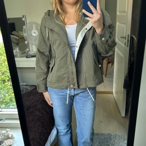 Grön jacka med luva - Grön jacka med luva och snören med två fickor på sidan