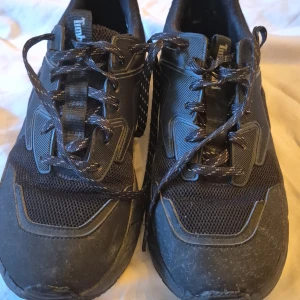 Svarta sneakers från Timberland - Säljer ett par svarta sneakers från Timberland. De är i bra skick med några mindre tecken på användning. Skorna har en robust sula och är gjorda av syntetmaterial med meshdetaljer för bättre andningsförmåga. De har snörning framtill och en bekväm passform.