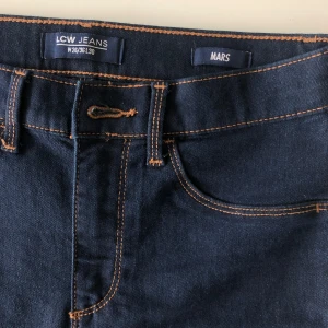 Mörkblå bootcut jeans från LCW Jeans - Säljer ett par snygga mörkblå bootcut jeans från LCW Jeans. De har en klassisk femficksdesign och är tillverkade i ett bekvämt jeansmaterial. Perfekta för både vardag och fest! 🖤(är i ett mjukt material)