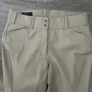 Ridbyxor  - Ridbyxor från ariat! Super fina beige ridbyxor, sömnen på insida lår har gått upp lite men ej något hål (se sista bilden) men syns bara när byxorna töjs ut🥰nypris 1599