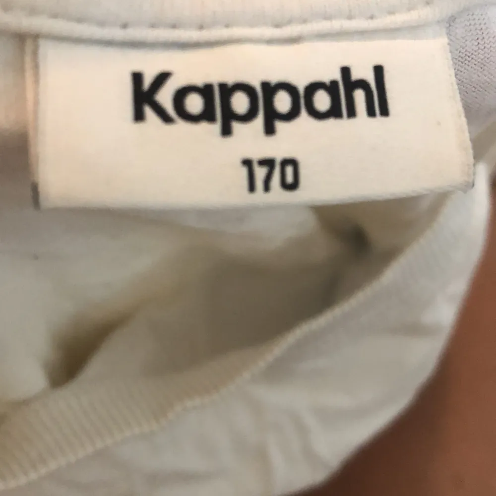 Säljer en enkel och stilren vit t-shirt från Kappahl. Den är i storlek 170 och passar perfekt för en avslappnad look. T-shirten är kortärmad och gjord av bomull, vilket gör den bekväm att bära. Perfekt för vardagsbruk eller som basplagg i garderoben.. T-shirts.