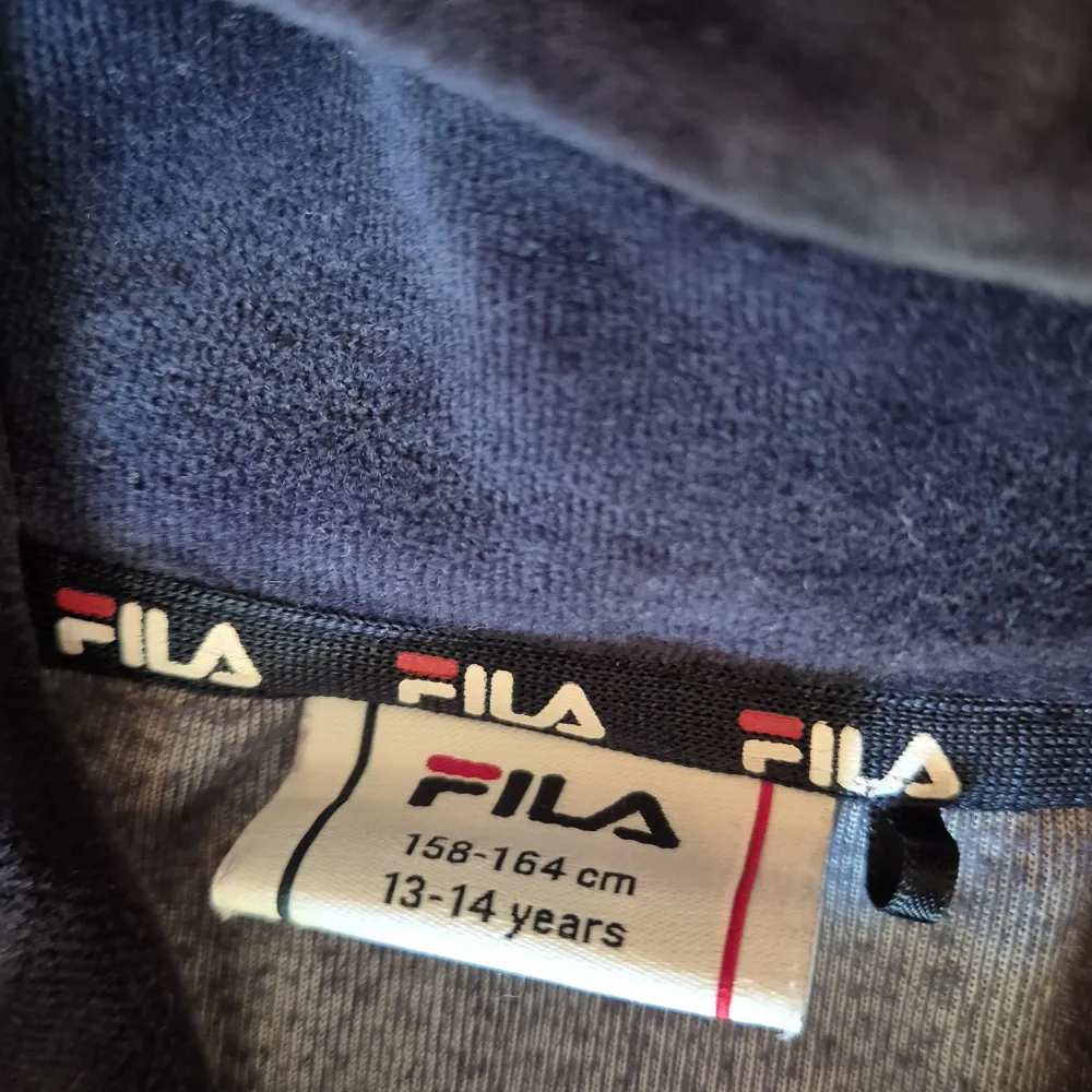 Säljer en snygg och bekväm hoodie från Fila. Den är blå med röda och vita detaljer, inklusive en stor röd F-logga på bröstet. Hoodien har långa ärmar med vita ränder och en röd sektion längst ner. Perfekt för höst och vinter!. Tröjor & Koftor.