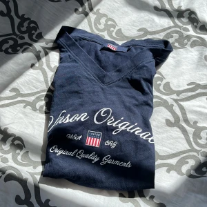 Mörkblå t-shirt från Vinson - Säljer en mörkblå t-shirt från Vinson i storlek S. T-shirten har en v-ringning och texten 'Vinson Original' tryckt på framsidan. Den är i bomull och passar perfekt för vardagsbruk. Skicket är bra. Perfekt för sommaren eller våren!
