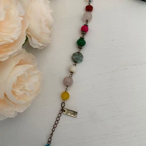 Färgglatt armband med pärlor - Säljer ett superfint armband med pärlor i olika färger. Armbandet har en mix av runda och facetterade pärlor i färger som röd, grön, gul, blå, rosa och vit. Det har också en liten metallbricka med texten 'Pure'. Perfekt för att lägga till en färgklick till din outfit!