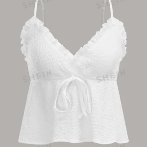 Vit croppad topp från SHEIN - Säljer en superfin vit croppad topp från SHEIN. Den har smala axelband och en v-ringad omlottdesign med volangdetaljer. Toppen är knytbar i midjan och är perfekt för sommaren. Materialet är lätt och luftigt, vilket gör den idealisk för varma dagar. Helt ny aldrif använd!!