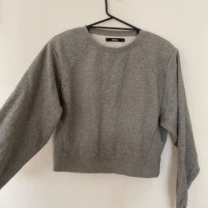 Grå croppad sweatshirt från Bik Bok - Säljer en superfin grå croppad sweatshirt från Bik Bok. Den är perfekt för höst och vinter med sitt mjuka och varma material. Tröjan har långa ärmar och en normal passform. Den är i nyskick och passar perfekt till både jeans och leggings. Perfekt för en casual look! 💖