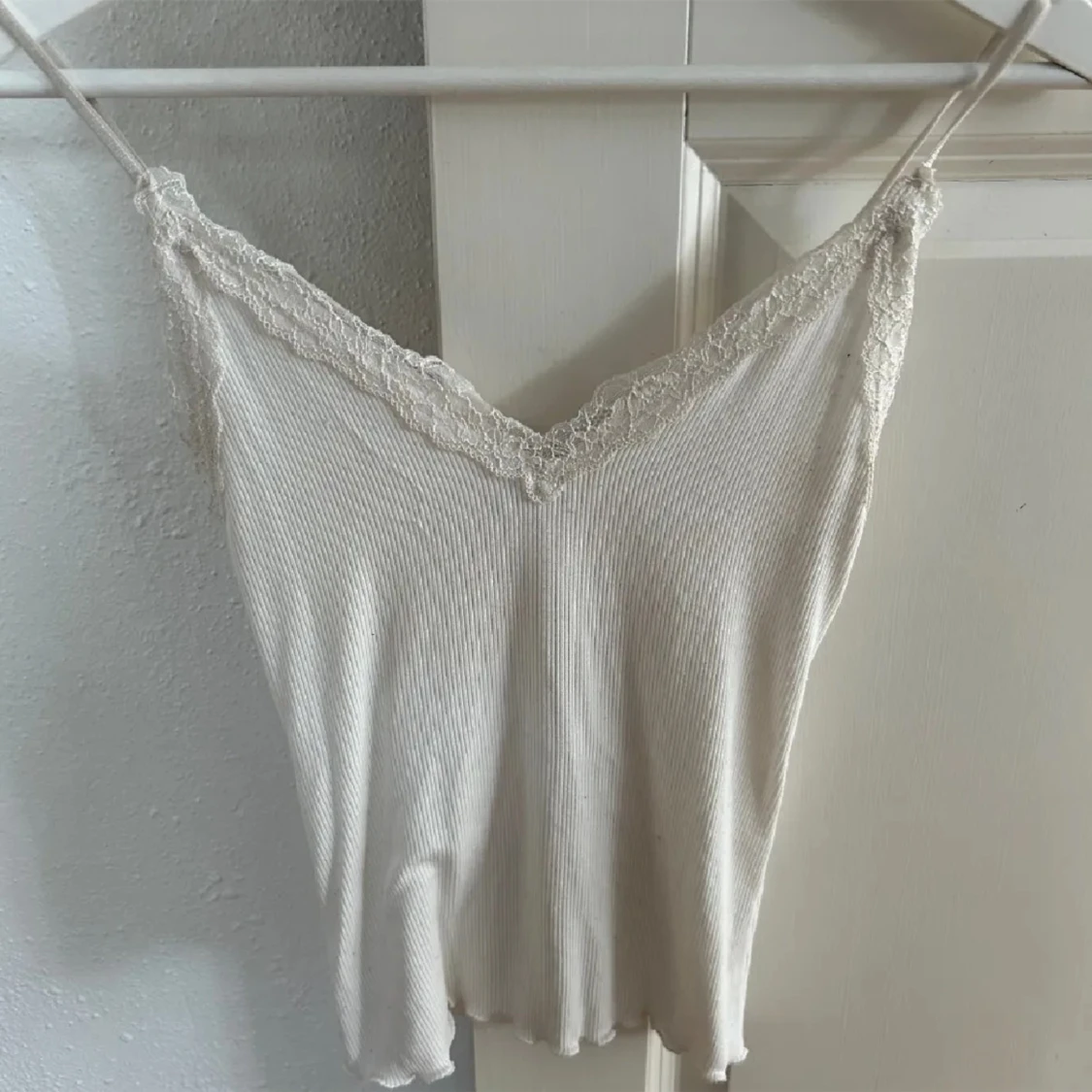 Vit ribbad linnetopp med spetsdetaljer