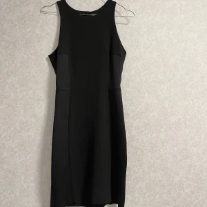 Svart ärmlös klänning - Säljer en elegant svart ärmlös klänning son är  knälängd. Klänningen är i nyskick och har en tight passform. 