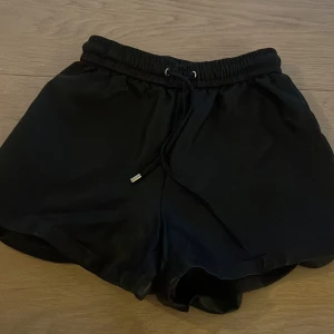 Svarta shorts från Amisu - Säljer ett par svarta shorts från new yorker i storlek 32. De är gjorda av ett mjukt och bekvämt material, perfekt för sommar och vår. Shortsen har en elastisk midja med dragsko för justerbar passform. De är i nyskick och har en normal passning. Perfekta för både träning och vardagsbruk! tappat bort ena silvriga grejen från snöret 