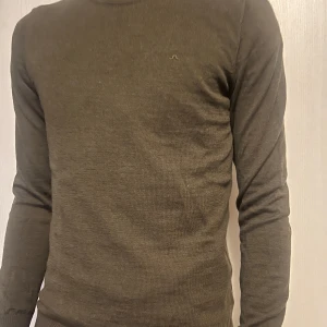 Olivgrön tröja från J.Lindeberg - Säljer en stilren olivgrön tröja från J.Lindeberg. Tröjan är långärmad och har en diskret logga på bröstet. Perfekt för en avslappnad men snygg look.