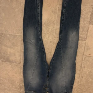 Blå jeans med knappar - Snygga blå jeans med en cool tvätt och knappar framtill. Perfekta för en avslappnad stil. De har en klassisk design med fem fickor och bälteshällor. Lapp saknas men är nog som 38