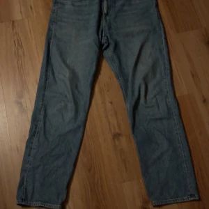 Blå jeansbyxor från &denim - Säljer ett par blå jeansbyxor från &Denim i relaxed fit. De har en klassisk design med dragkedja och knapp framtill. Perfekta för en avslappnad stil.