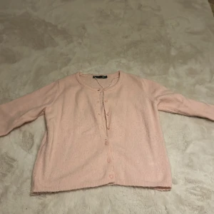 Ljusrosa kofta från 157 - Mysig ljusrosa kofta från 157 med rund halsringning och knappar framtill. Bra sick då den bara använts ett par gånger. Jätteskön kofta! 