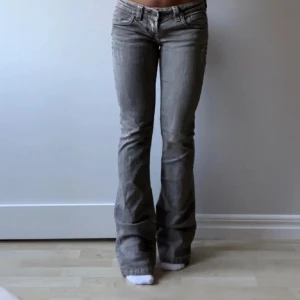 Lågmidjade grå bootcut jeans - Snygga grå bootcut jeans med detaljer på bakfickorna. Dock har jag målat det gula på bakfickorna till svart. Midjemått tvärsöver 38cm, innerbenslängd 82cm❤️Lånade bilder! Säljer då de inte har kommit till användning.