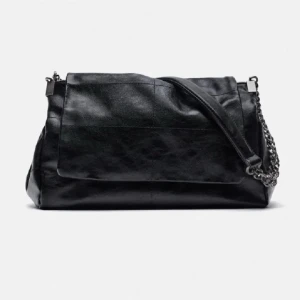 Svart axelväska med kedjedetalj - Snygg svart axelväska i skinn med en cool kedjedetalj på axelremmen. Väskan har en praktisk dragkedja och en stilren design som passar perfekt för alla tillfällen. Enkla linjer och en elegant look gör den till ett måste i garderoben. Väskan är i användt men väldigt fint skick💕