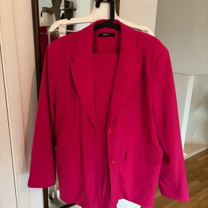 Rosa kostym Gina  - Kavaj: oversize modell fint skick enbart en liten reva på insidan men det syns ej (se bilder). Satin på insidan. Strl L men som XL därav lägre pris  Byxan: snygga rosa kostym byxor med lossas ficka bak. Strl 