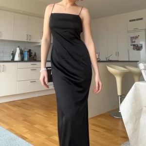 Svart långklänning med smala axelband - Elegant svart långklänning med smala axelband och öppen rygg. Passar utmärkt till studentbal. Aldrig använd, bara testad, prislapp kvar