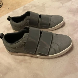 Grå sneakers från Lacoste - Unika Lacoste sneakers i grå vit, inte så andvända och är väldigt sköna och snygga kan diskutera priset 