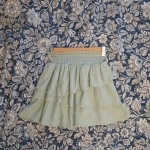 Ljusgrön volangkjol - Charmig ljusgrön kjol med flera lager volanger. Perfekt för en somrig look. Kjolen har en elastisk midja för bekväm passform.