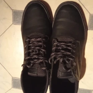 Svarta sneakers från Lacoste - Snygga svarta sneakers från Lacoste med snörning och diskret logga på sidan. Skorna har en stilren design med en ovandel i skinn och en bekväm sula. Perfekta för en casual look.