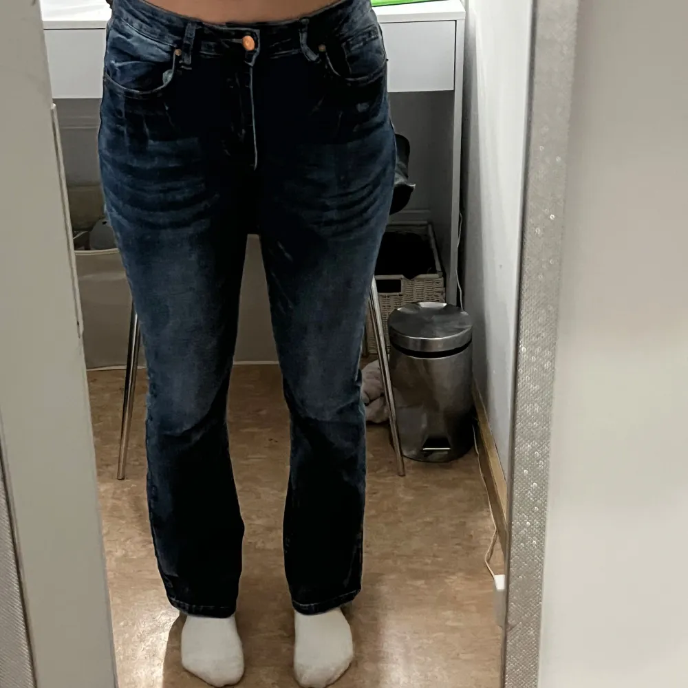 Säljer ett par mörkblå bootcut jeans med hög midja. Jeansen har en klassisk femficksdesign och en knappgylf. Perfekta för en avslappnad stil.. Farkut & Housut.