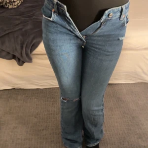 Blå jeans från gina - Snygga blå jeans från Gina tricot, hål vid knät och slitning där uppe. De är för små för mig så kan inte stänga dom men dragkedjan funkar. Slitet där nere men inget man tänker på.